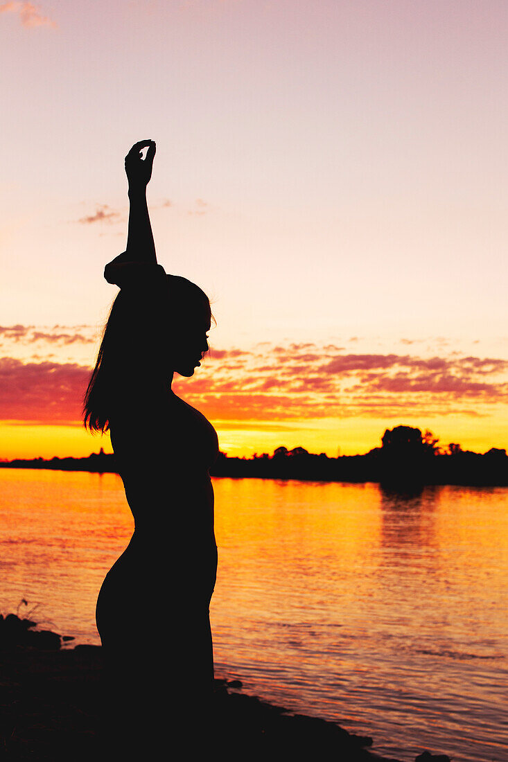 Silhouette of a woman arms up in sunset