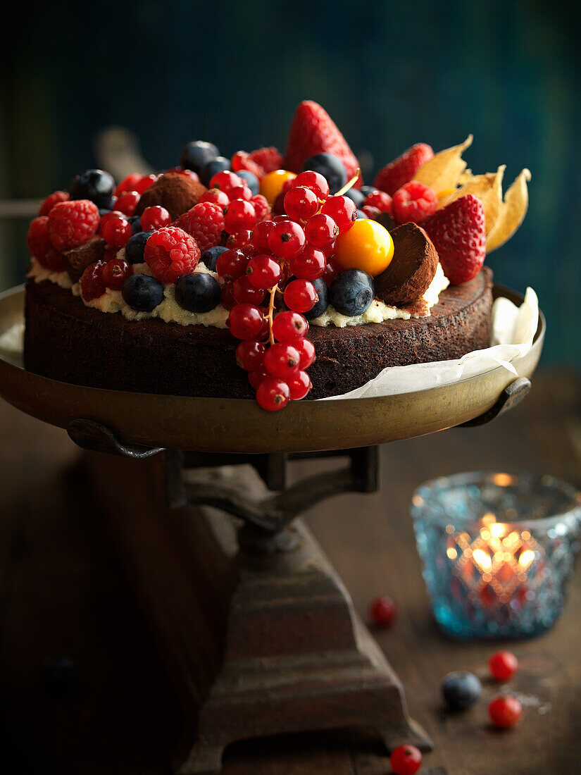 Dunkler Schokoladenkuchen üppig dekoriert mit Zuckerguss und Früchten