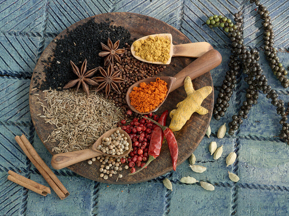 Various spices on small wooden scoops and a wooden board