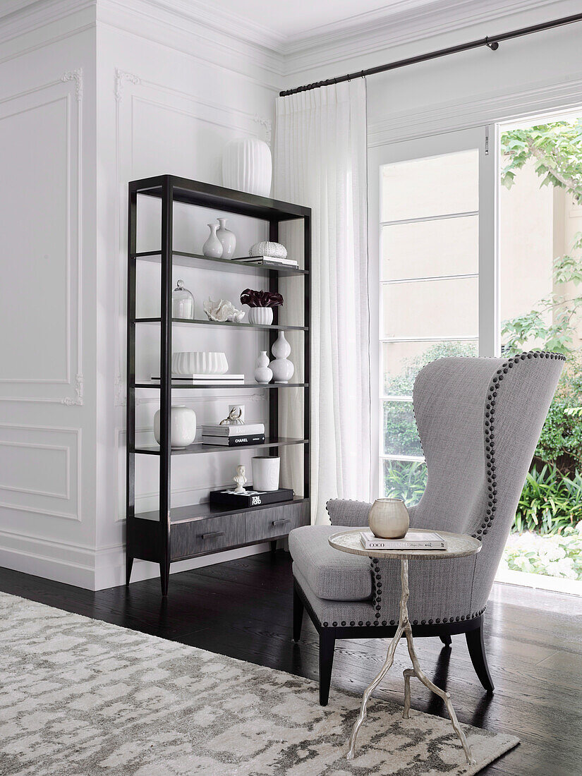 Wing chair with side table and shelf with decorative objects in living room