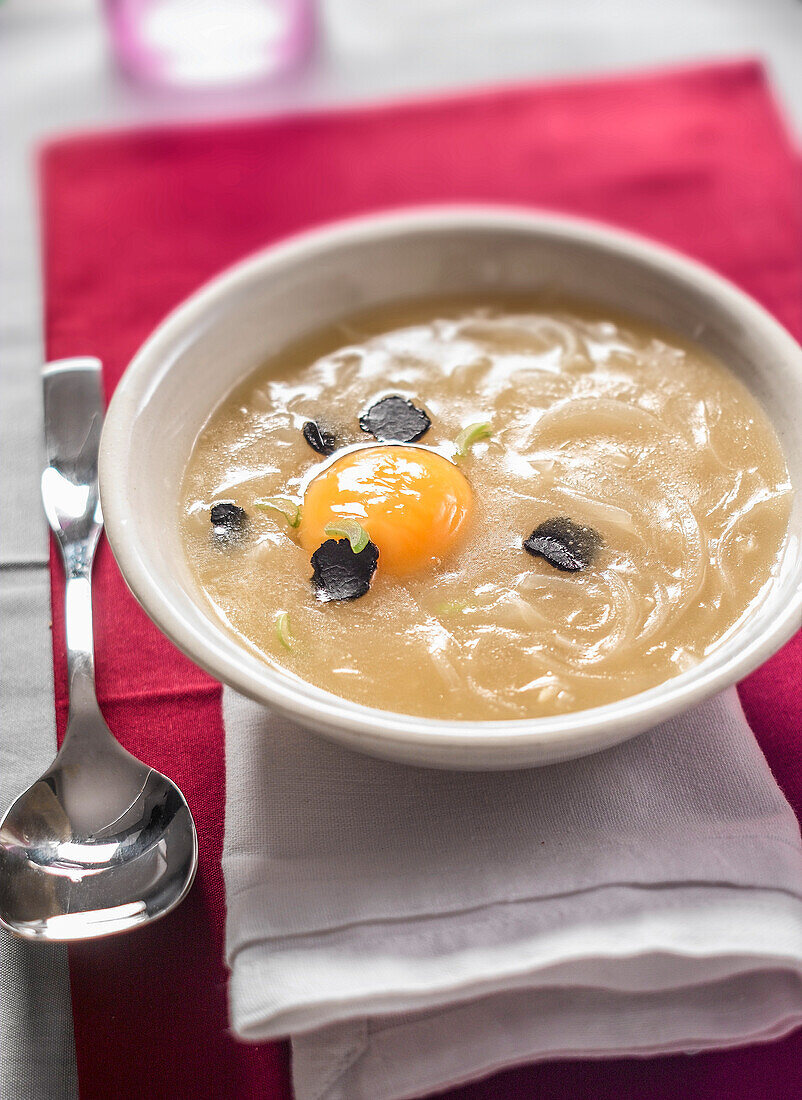 Zwiebelsuppe mit rohem Ei und schwarzem Trüffel