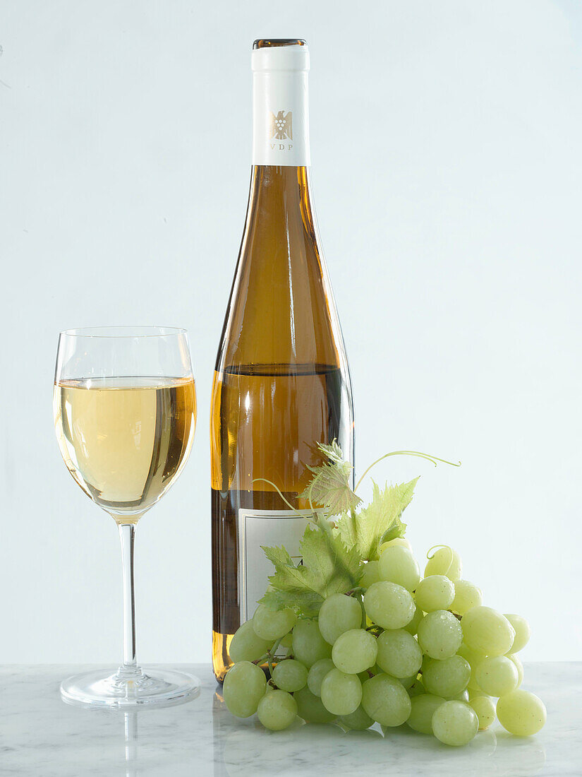 Glass and bottle of white wine with grapes