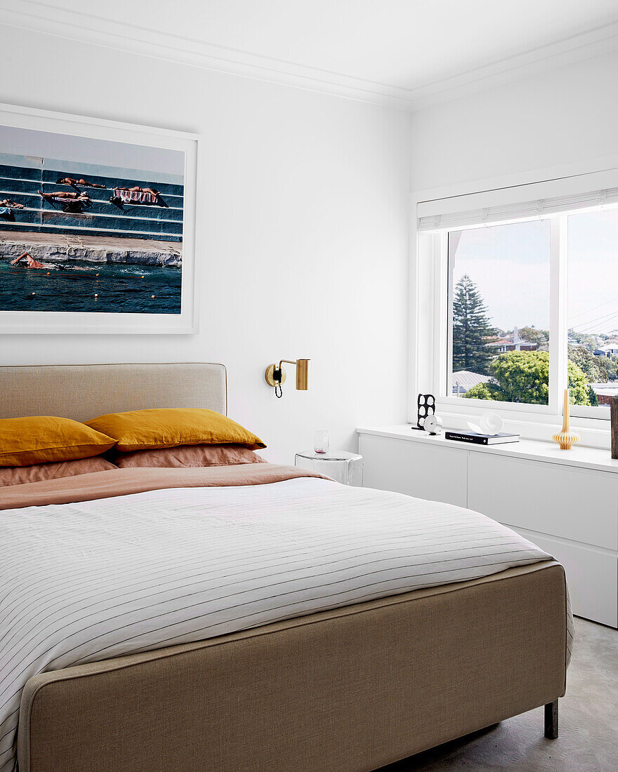 Doppelbett, darüber Bild in weißem Schlafzimmer mit Fenster