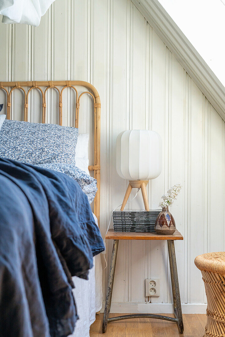 Stool used as a bedside table in a bedroom with a wood paneled wall