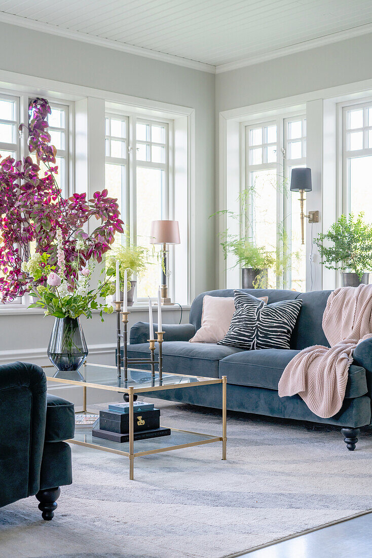 Coffee table with flowers and grey velvet sofa in bright living room