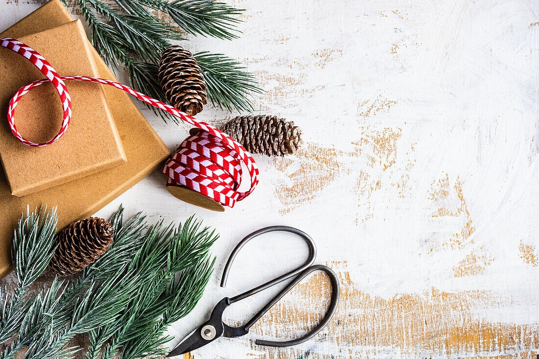 Geschenkboxen, Band und Winterdekoration auf altem weißem Holztisch