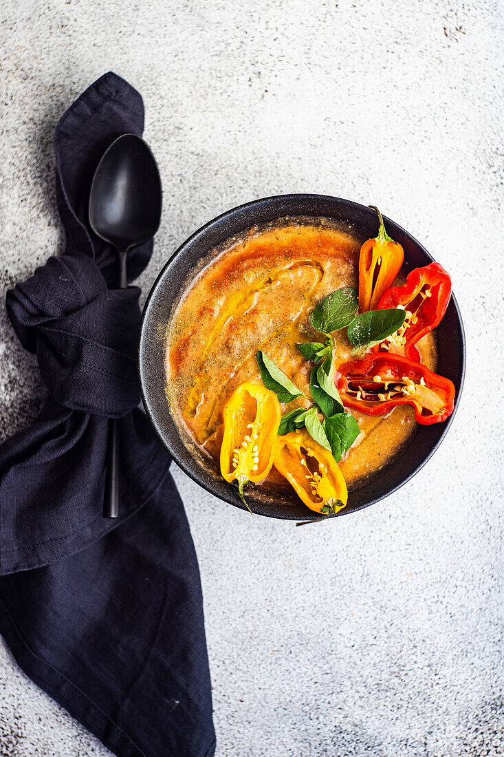 Creamy spicy chick pea soup served with chili pepper slices and fresh oregano herb