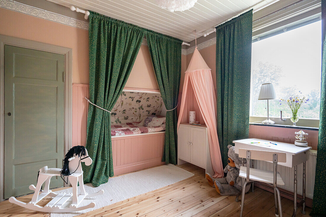 Eingebautes Bett im Mädchenzimmer mit rosa Wänden und grünen, bodenlangen Vorhängen