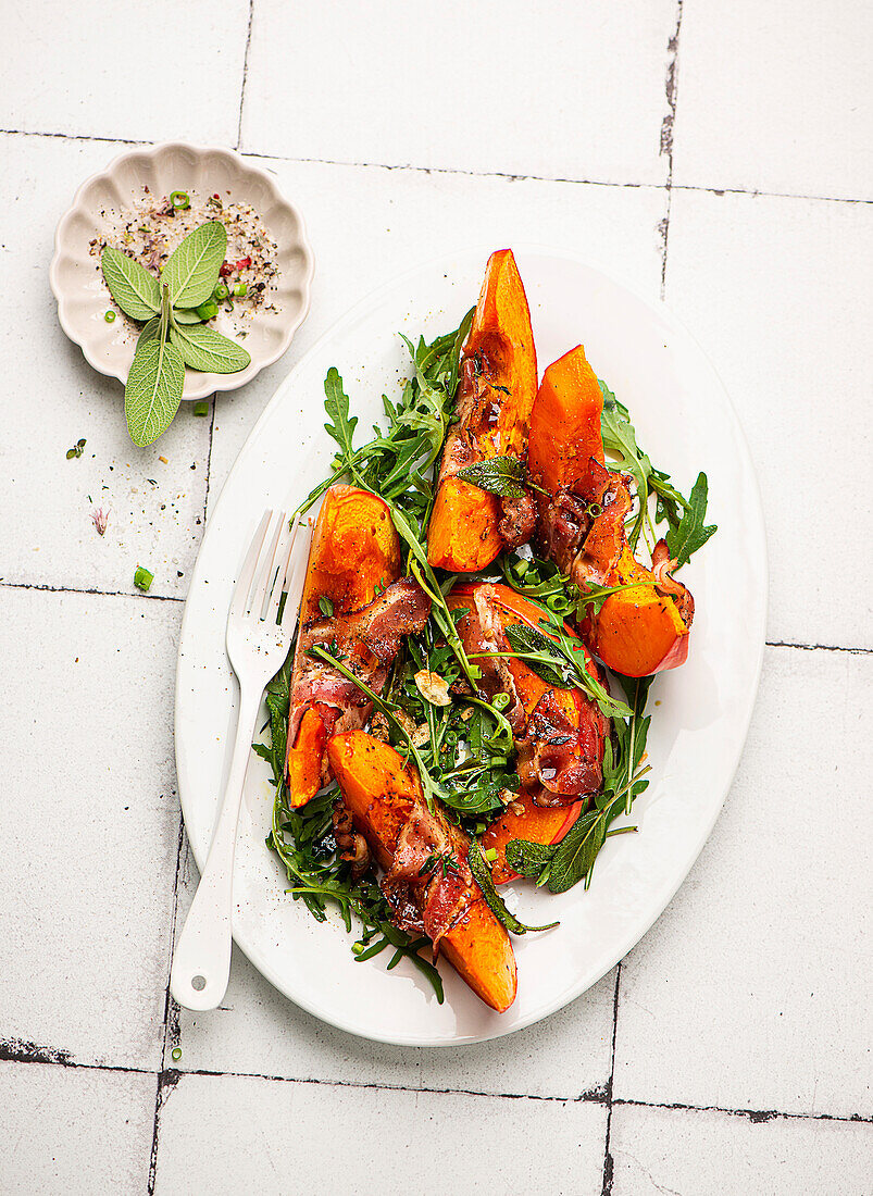 Pumpkin slices wrapped in bacon on rocket salad