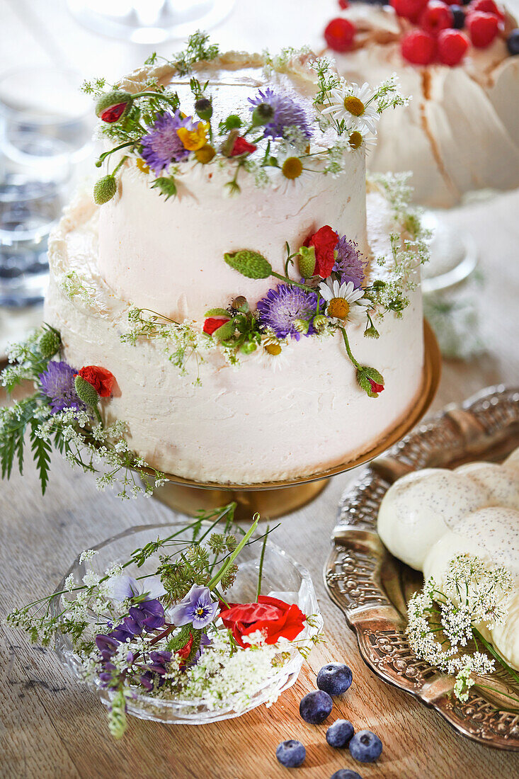 Weiße, zweistöckige Torte mit Wildblumen verziert