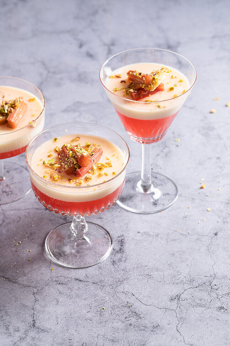 Rhubarb jelly and panna cotta served in vintage glasses, topped with poached rhubarb and chopped pistachios