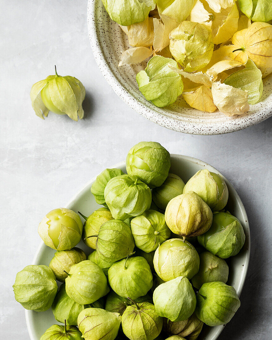 Bowls of tomatillos and tomatillo husks