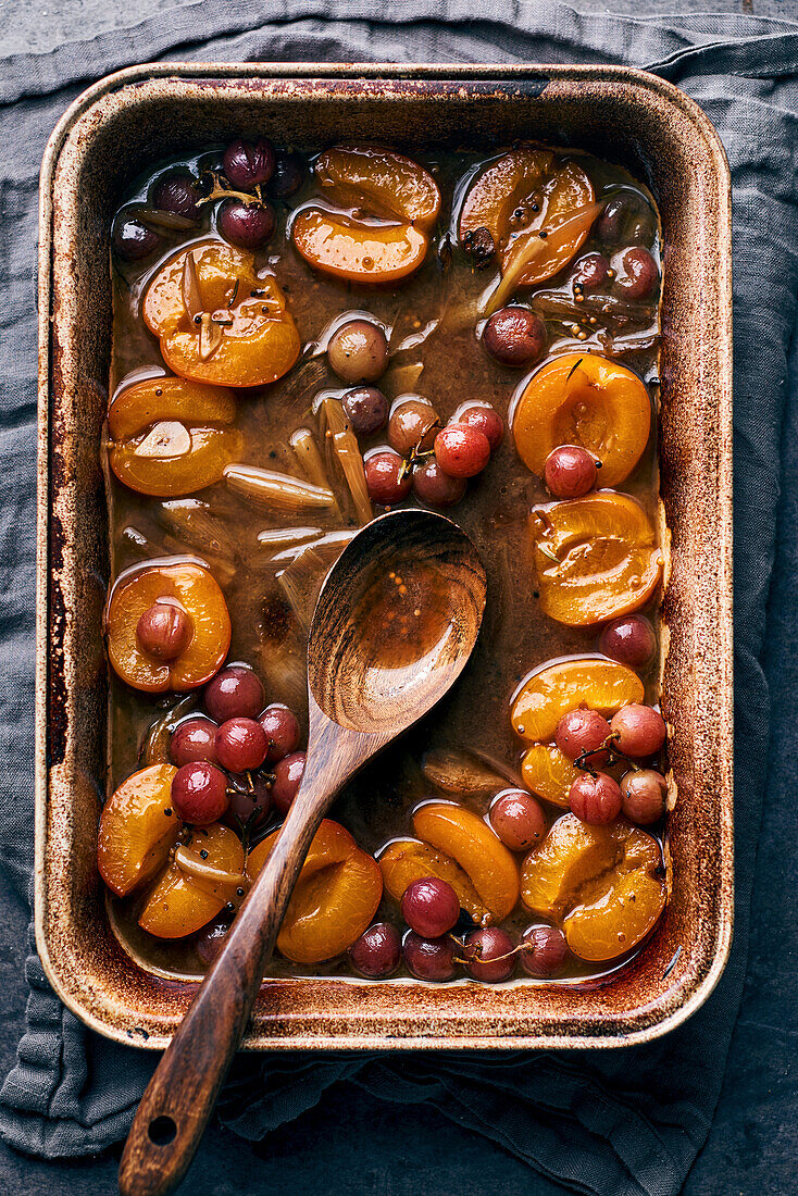 Au jus from a pork roast with roasted fruits and vegetables (apricots, grapes, and shallots)