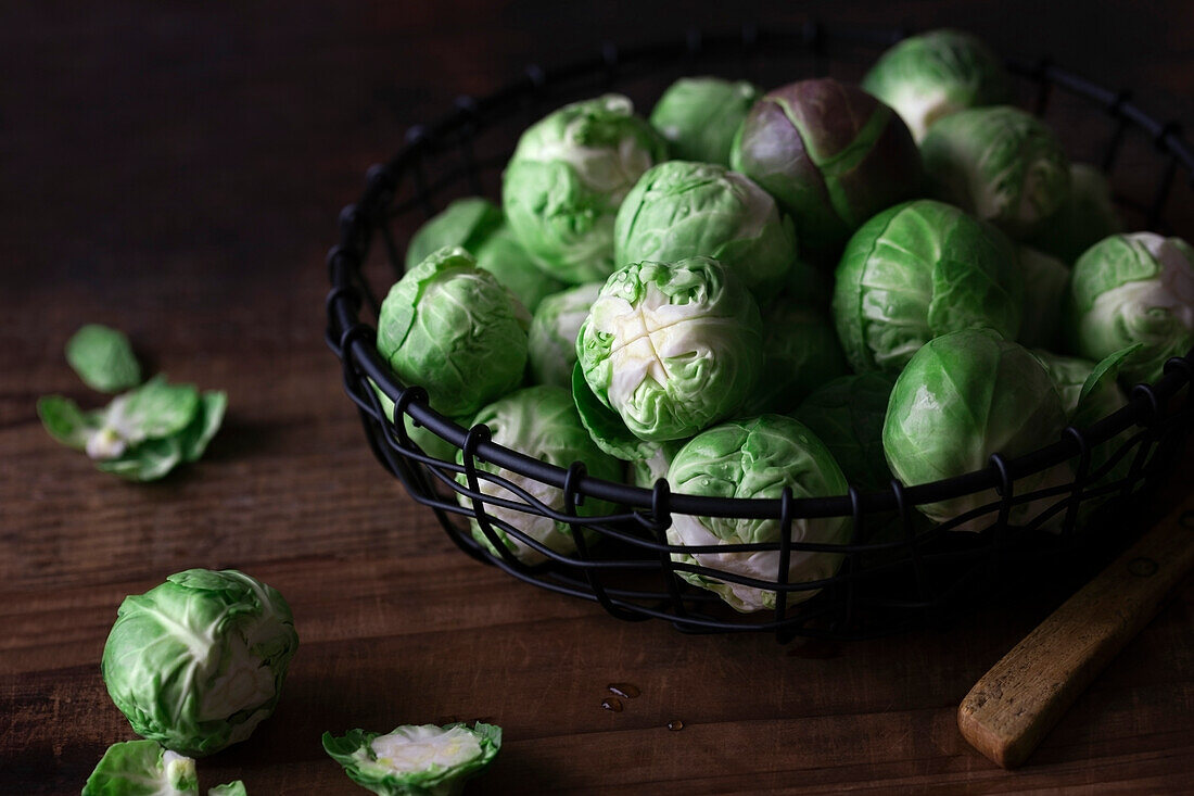 Frischer Rosenkohl im Drahtkorb auf Holzuntergrund