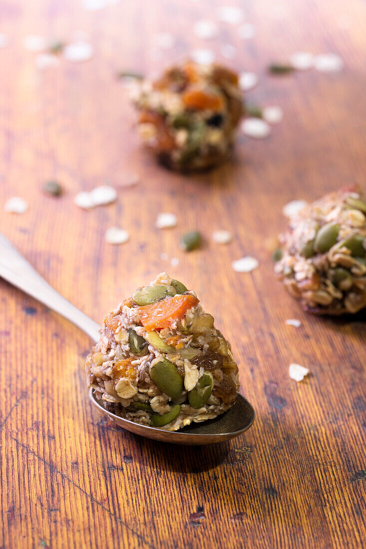 Healthy muesli cookie mixture rolled into balls with one on a spoon