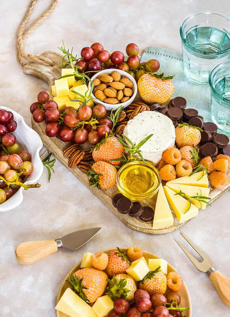 Cheese board with nuts, fruits, berries and chocolate