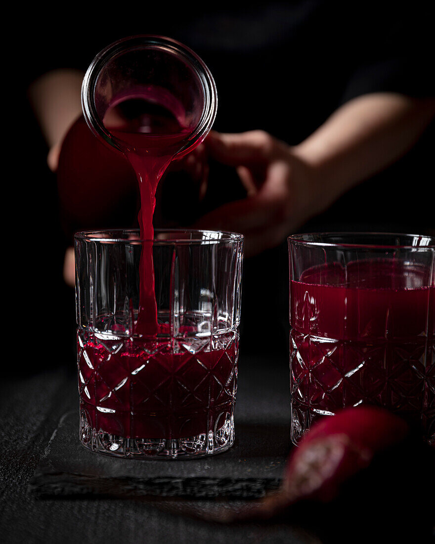 Freshly squeezed beet juice being poured into a decorative glass