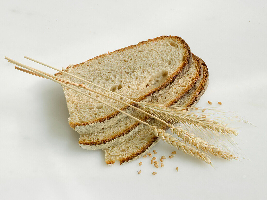 Three slices of German gray bread and ears of grains