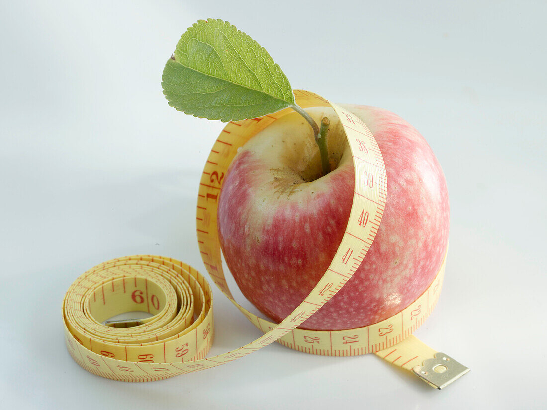 Ein Apfel mit Blatt, umwickelt mit einem Maßband