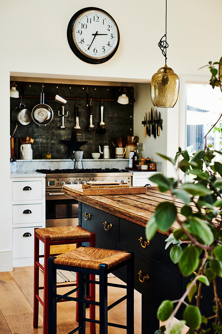 Blue kitchen island with reclaimed wood worktop, bar stool and large clock above gas stove