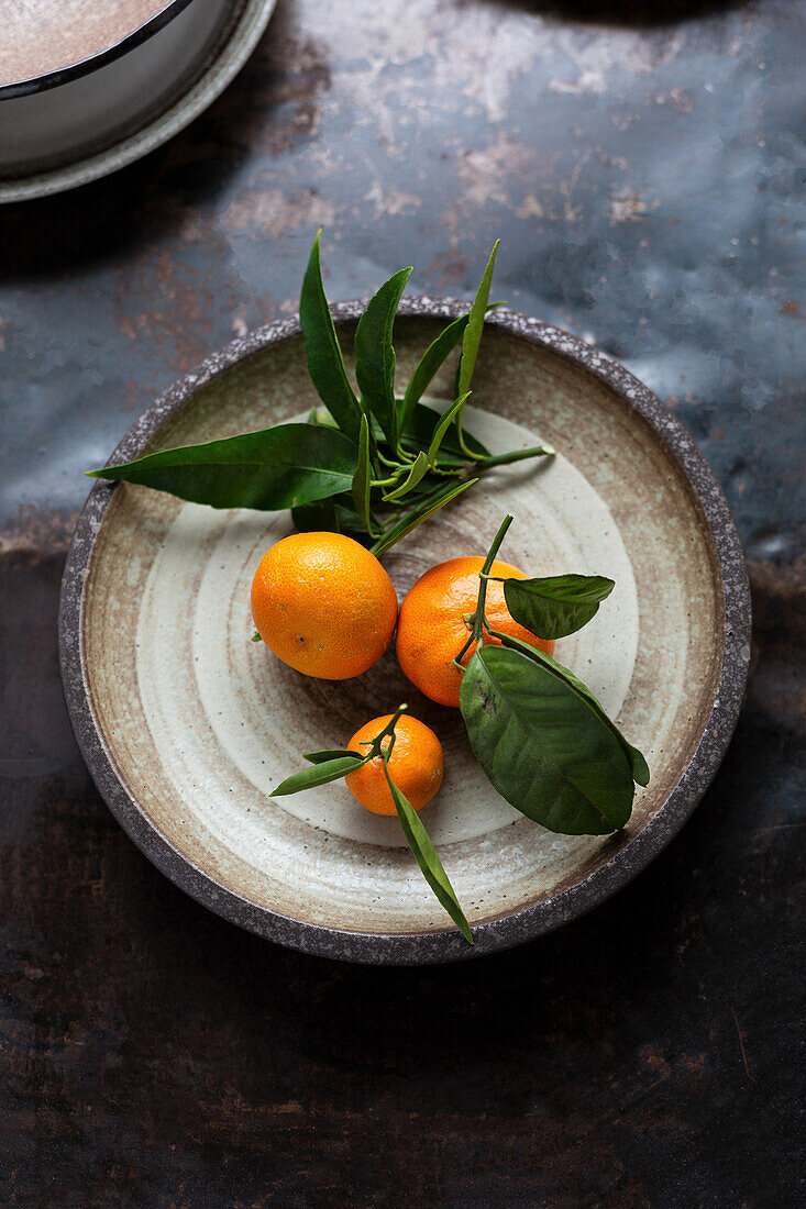 Mandarinen mit Blättern auf einem Teller