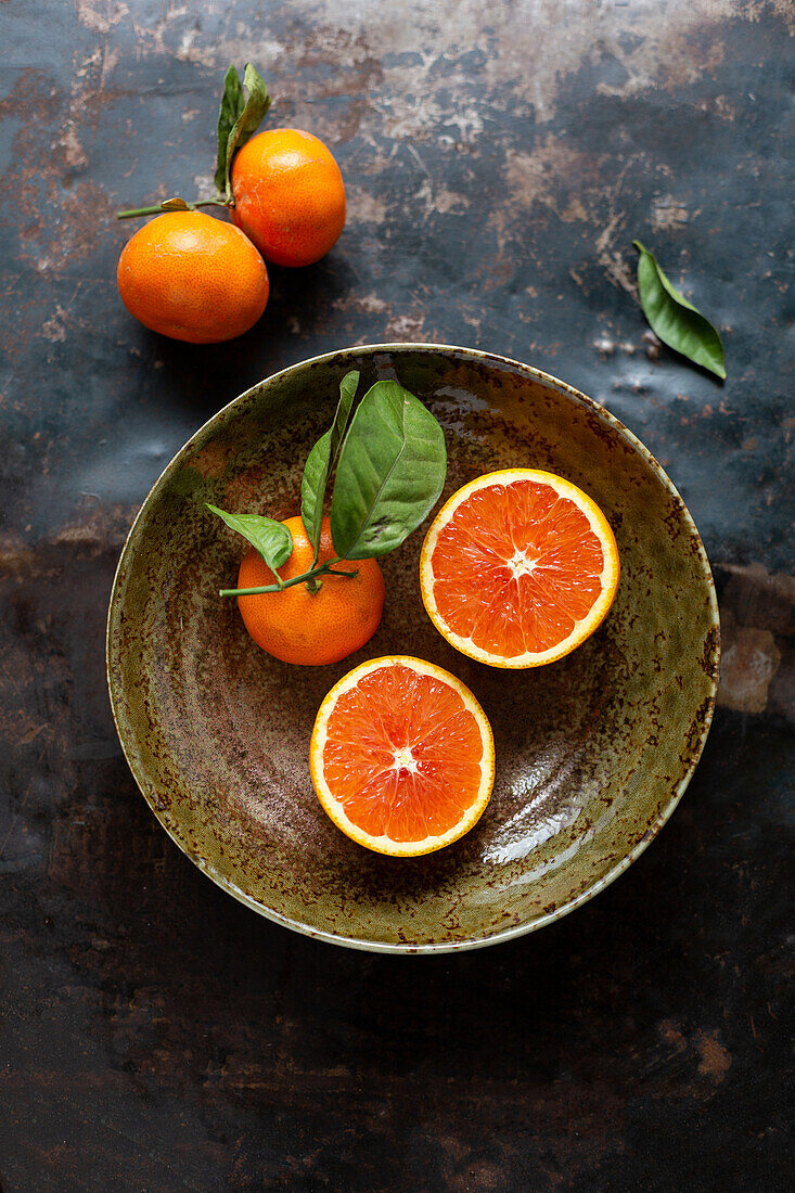 Blood oranges, whole and halved in a ceramic bowl