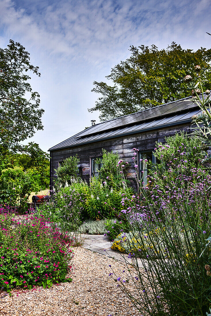 Sommerlicher Garten, Gartenhaus aus Holz mit Sonnenkollektoren auf dem Dach