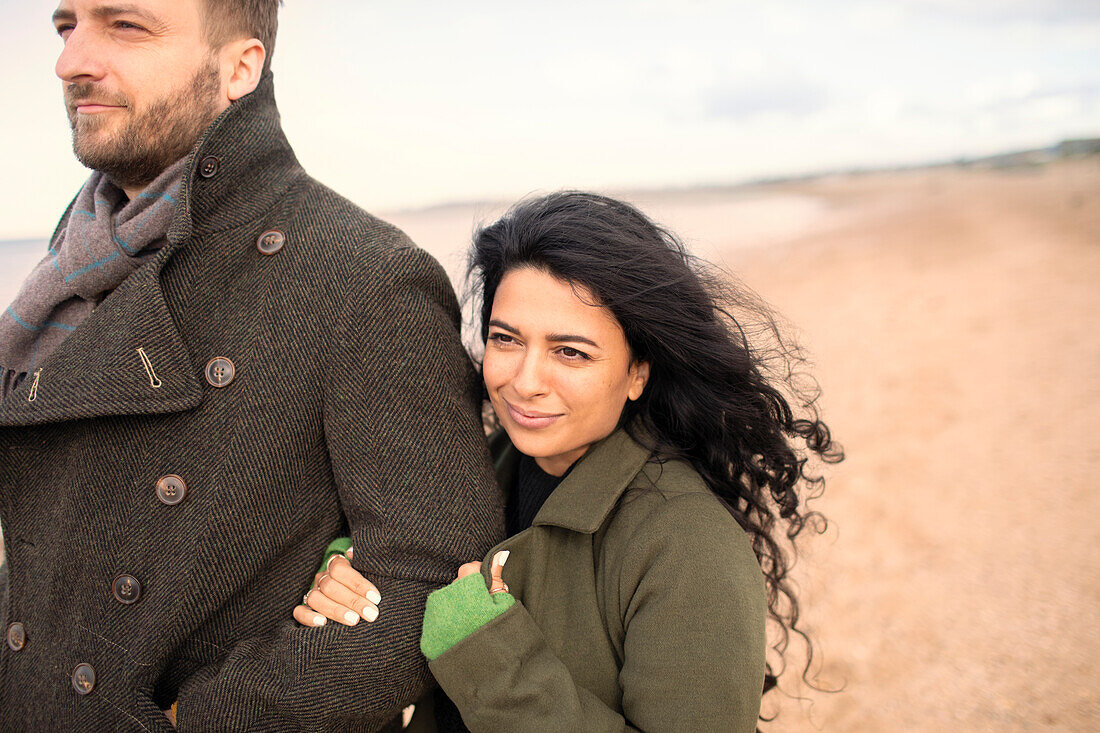 Happy couple in winter coats on beach