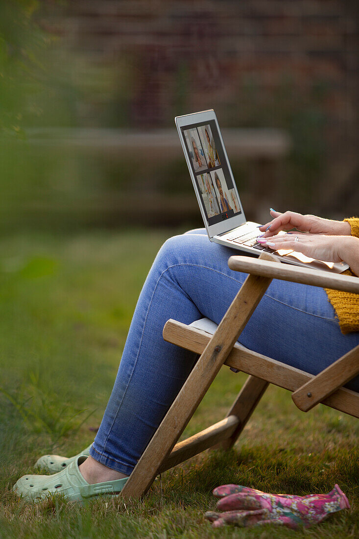 Woman using laptop in garden lawn chair