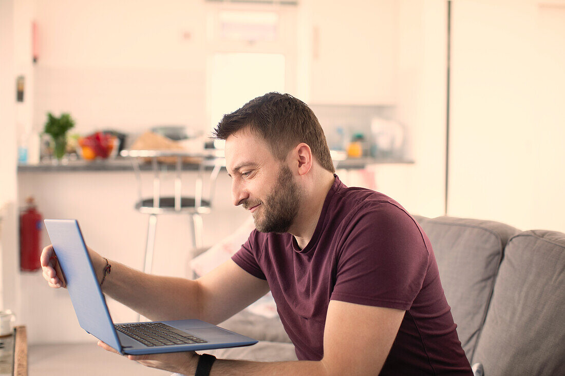 Man working from home on laptop on sofa