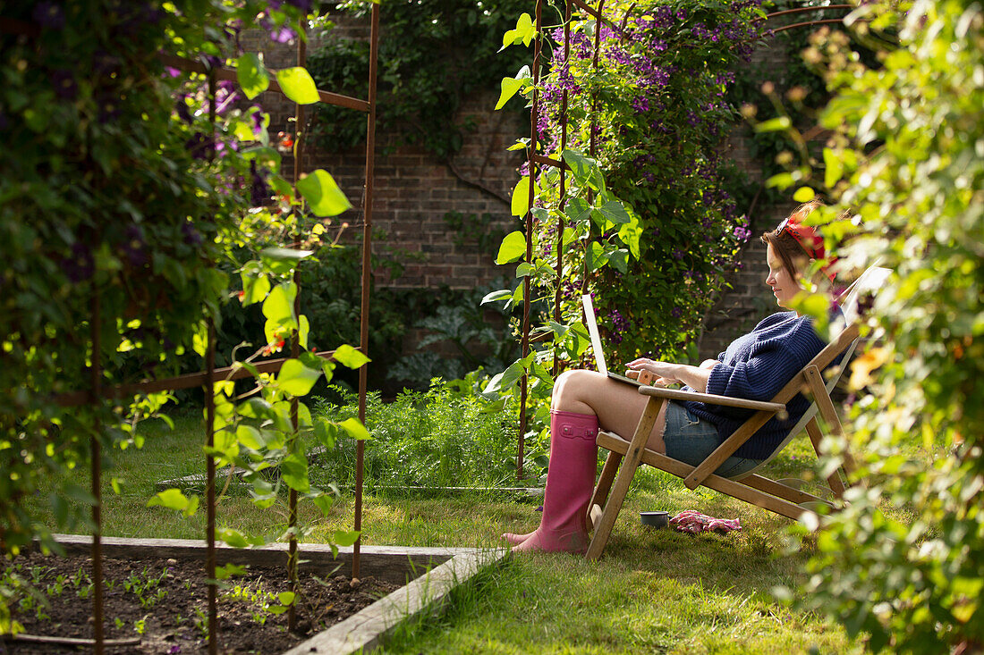 Woman using laptop in sunny summer garden