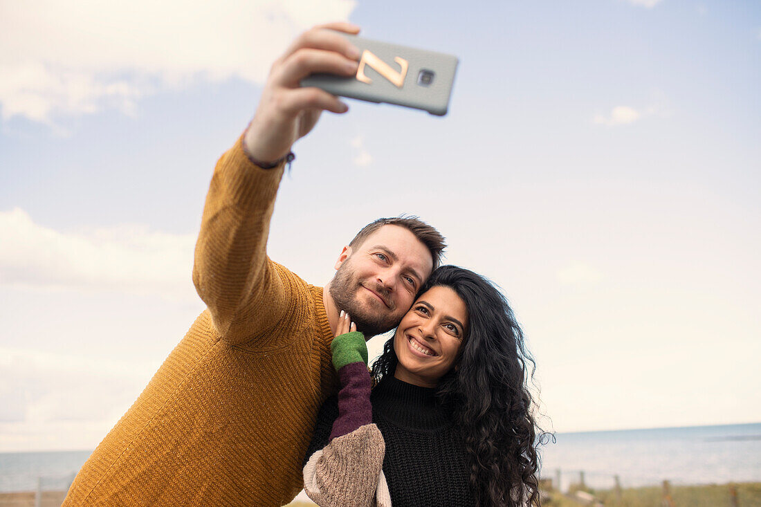 Happy couple taking selfie on beach