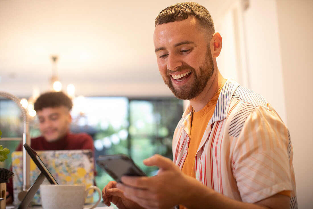 Happy young man using smart phone at home