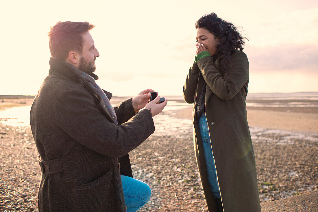 Man proposing to girlfriend on sunny winter beach