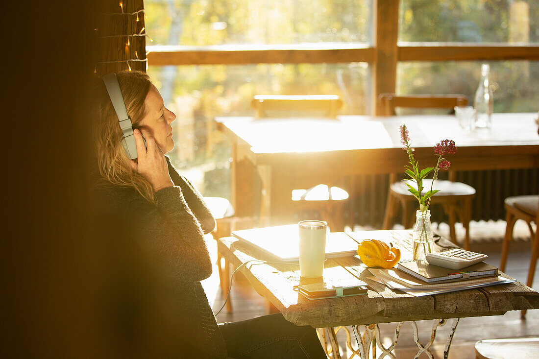 Businesswoman with headphones working in sunny cafe