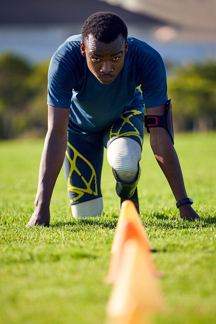 Focused amputee sprinter doing sports drills in grass