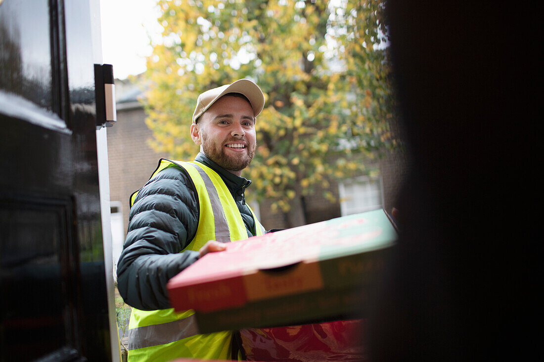 Friendly delivery man delivering pizza at front door