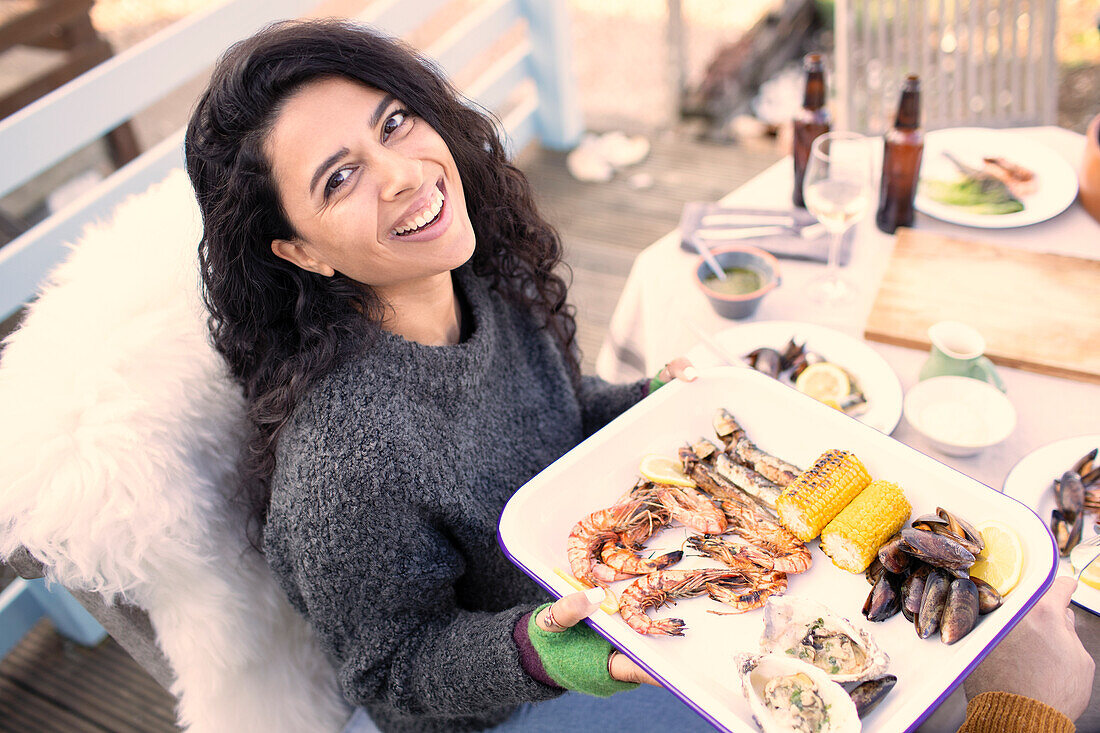 Happy woman with fresh seafood at patio table
