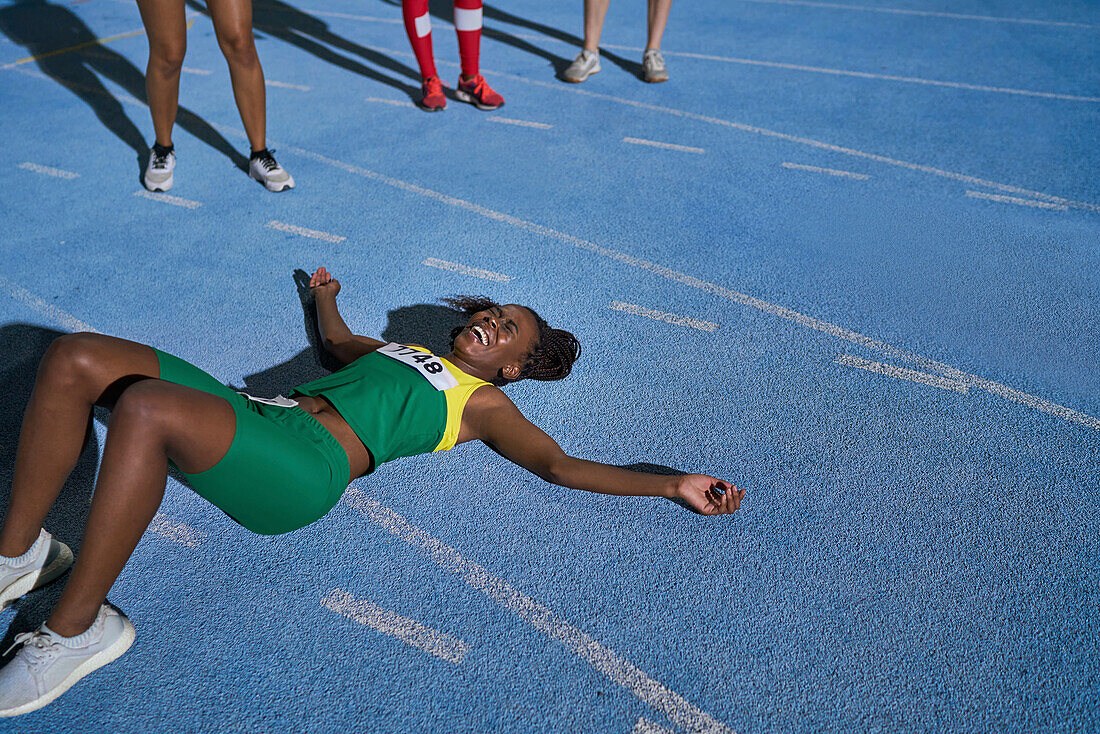 Tired track and field athlete laying on sunny track