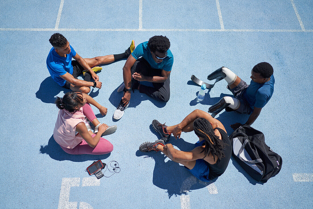 Young athletes talking on sunny blue sports track