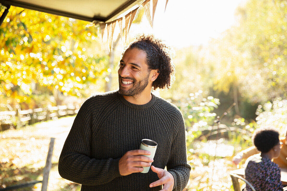 Happy man with coffee in sunny autumn park