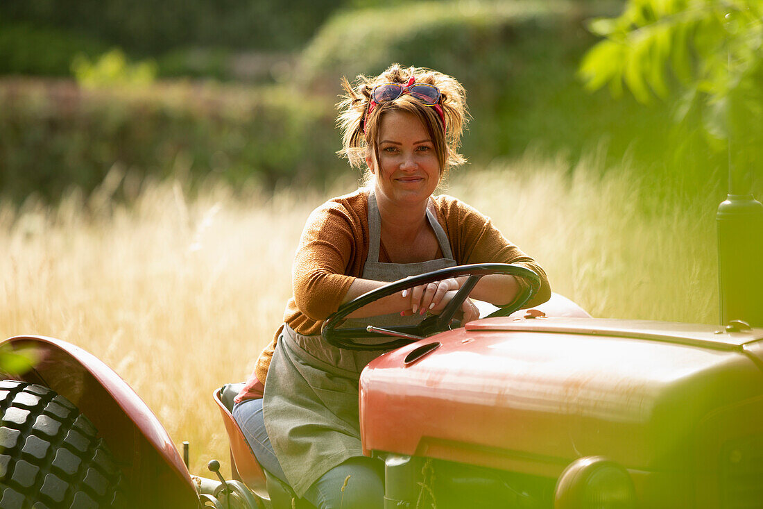 Happy female farmer driving tractor