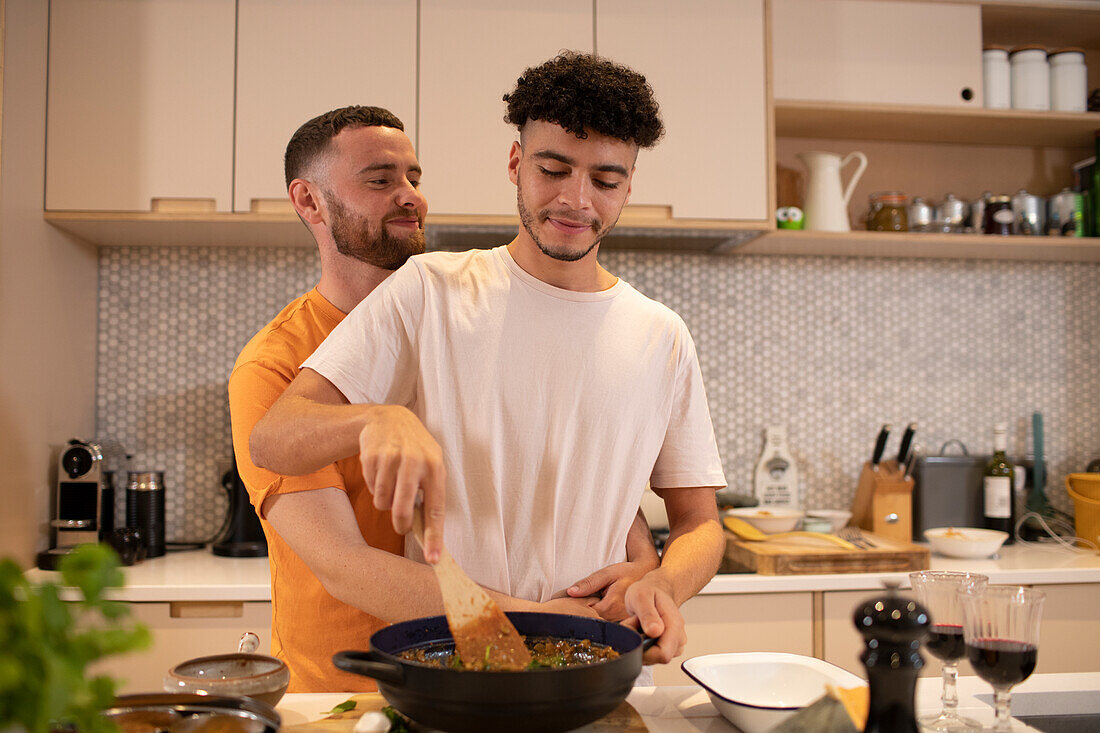 Affectionate gay male couple cooking in kitchen