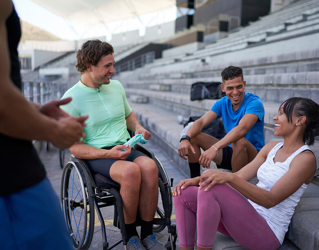 Happy athletes laughing and talking in bleachers