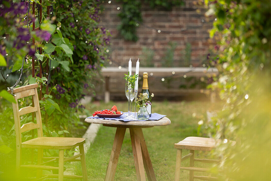 Champagne and red currants on garden table with candles