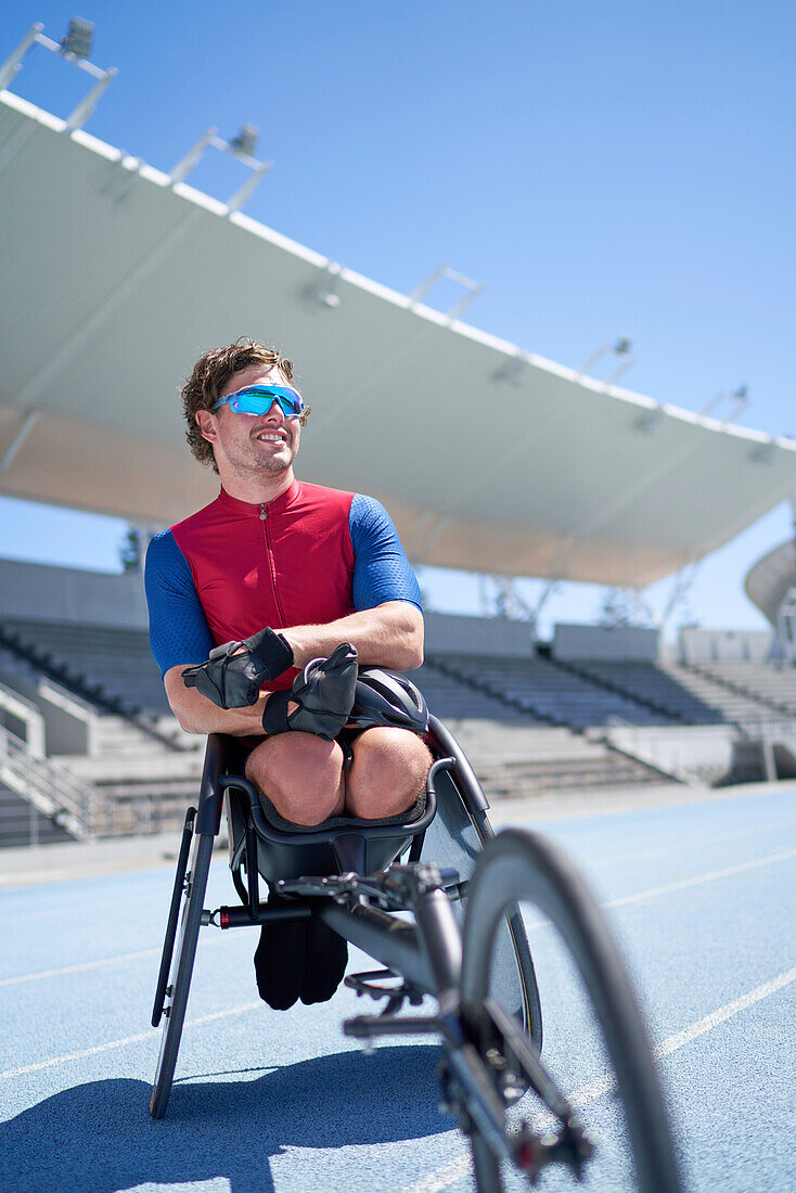 Confident male wheelchair athlete on sunny sports track