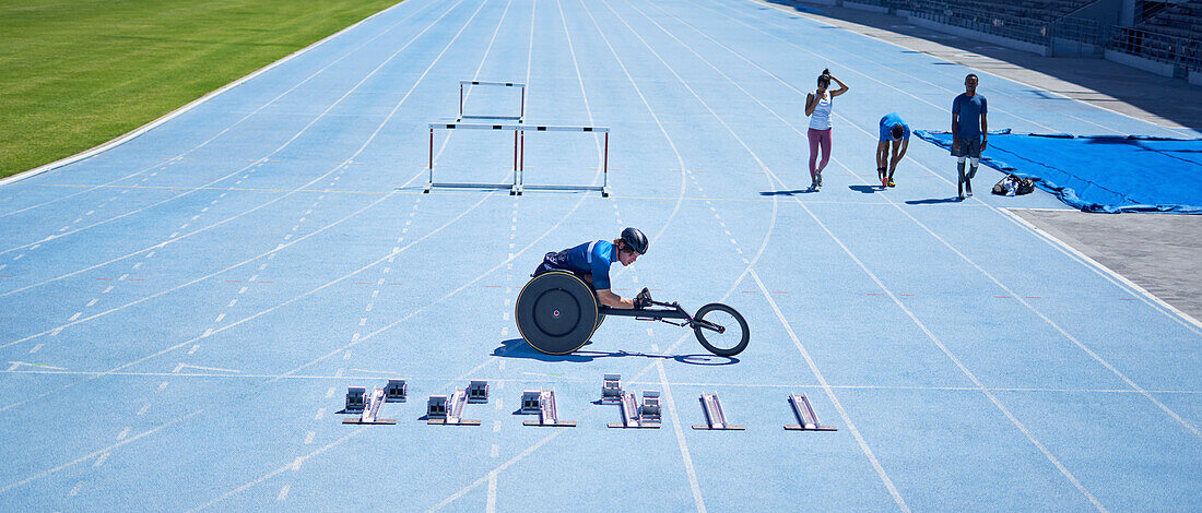 Wheelchair athlete preparing on sunny blue sports track