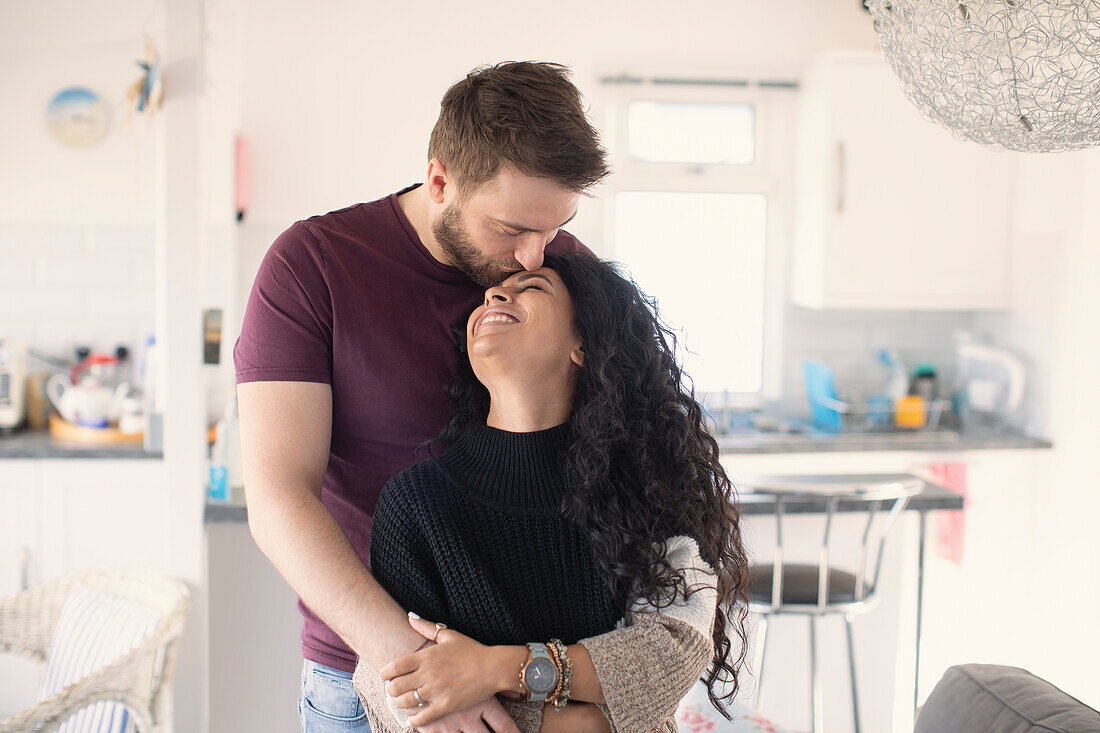 Happy affectionate couple hugging and kissing in kitchen