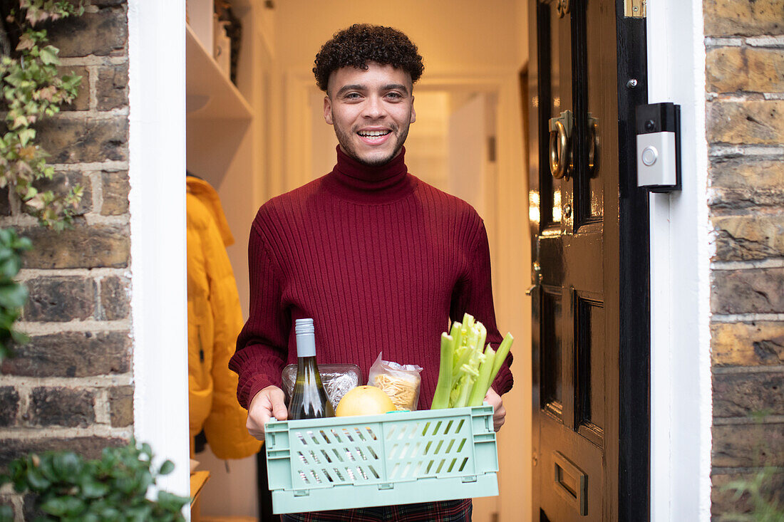 Happy young man receiving grocery delivery at front door