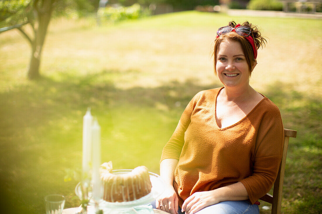 Happy woman enjoying cake at table in sunny summer garden